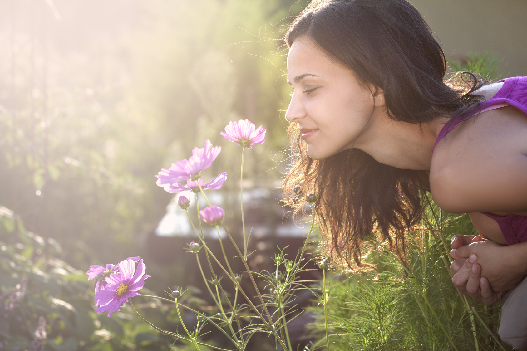 Young beautiful woman smells a flower in the garden